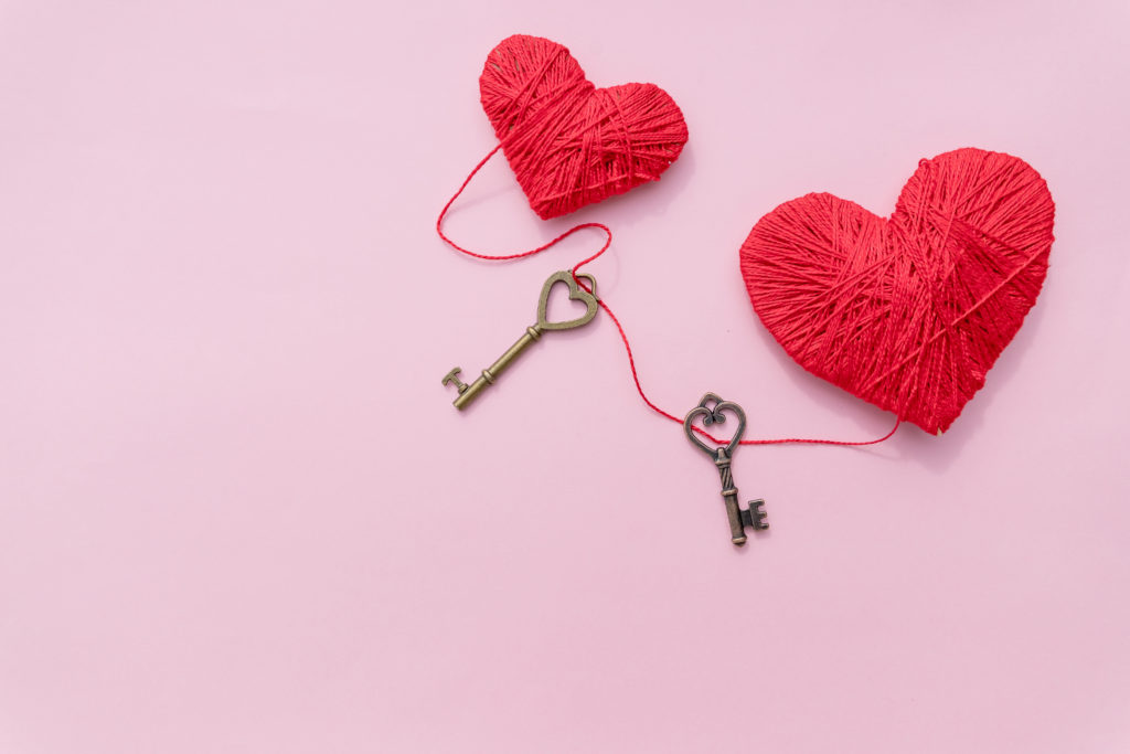 Decorative red heart and small metal key against pink background.Festive romantic image for Valentine's Day. Copy space. Holidays postcard about love and feelings